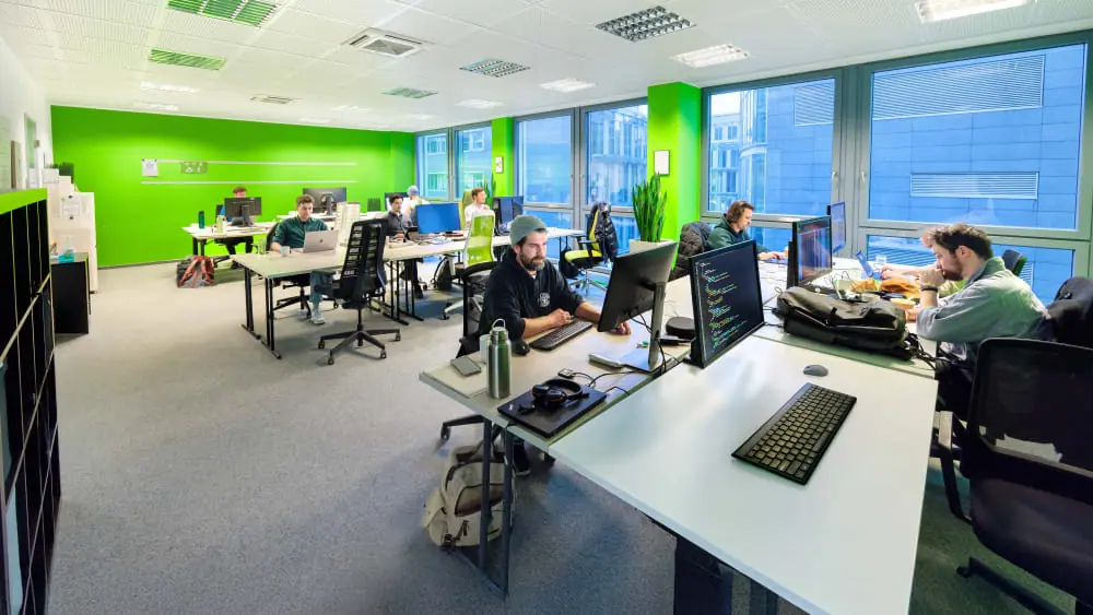 Blick in das Büro von LimeByte im Kölner Mediapark: offener Raum, limettengrüne Wand, Arbeitsplätze mit mehreren Bildschirmen.